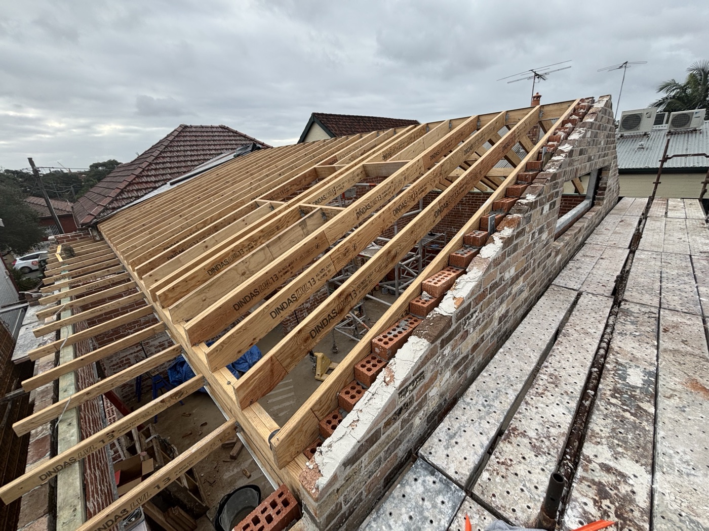 New roof framing meeting a heritage brick parapet