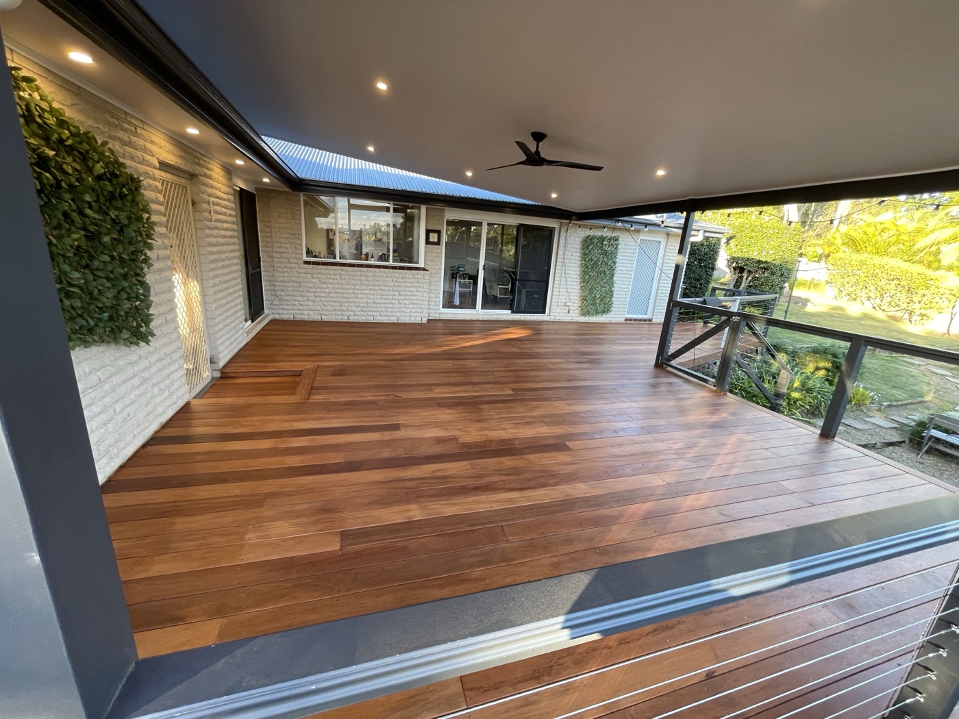 Covered timber deck alongside brick home